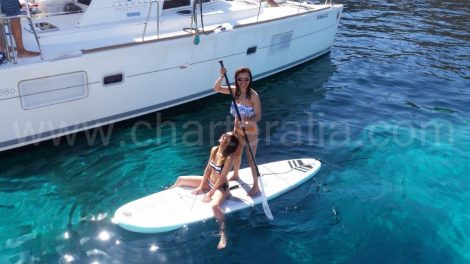 Mädchen auf dem paddleboard neben dem Katamaran in Ibiza