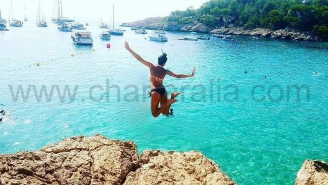 Cliff jumping between Cala Salada and Cala Saladeta with a view of yacht charters in Ibiza