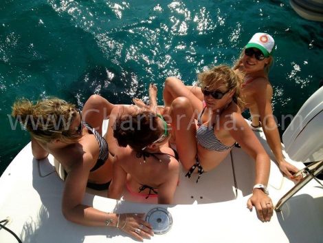 Klanten zitten op een zwemplatform met catamaran voor charter op Ibiza