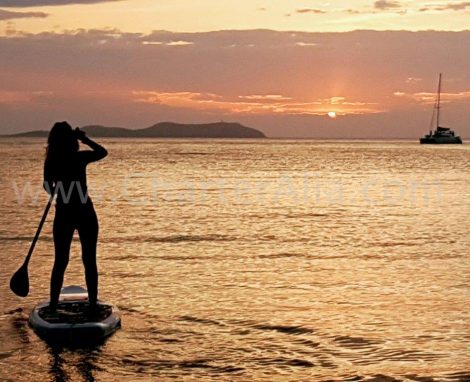 Paddle surfen op de zonsondergang tijdens catamaranverhuur met overnachting