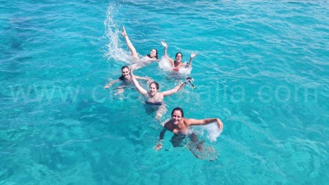 chicas en Ibiza nadando hacia el barco de alquiler