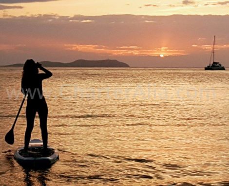 Paddle Surfen in den Sonnenuntergang waehrend des Katamarans Vermietung mit Uebernachtung