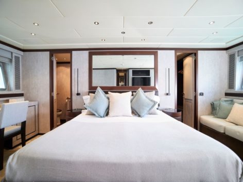 Large owners suite of the Mangusta 92 yacht with private bathroom dressing room sofa and desk