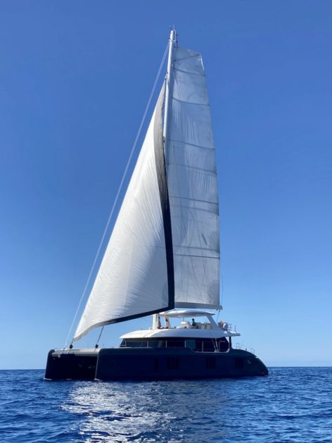 Side view of the impressive SunReef 70 catamaran sailing in the waters of Formentera